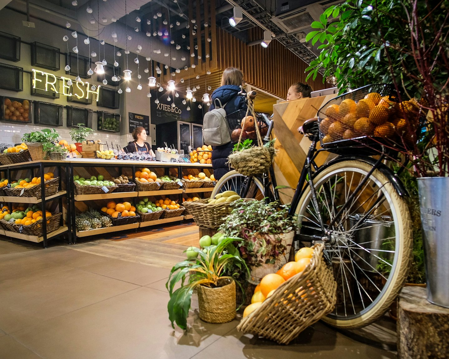 Klienci i personel rozmawiają w sklepie spożywczym ze świeżymi produktami.