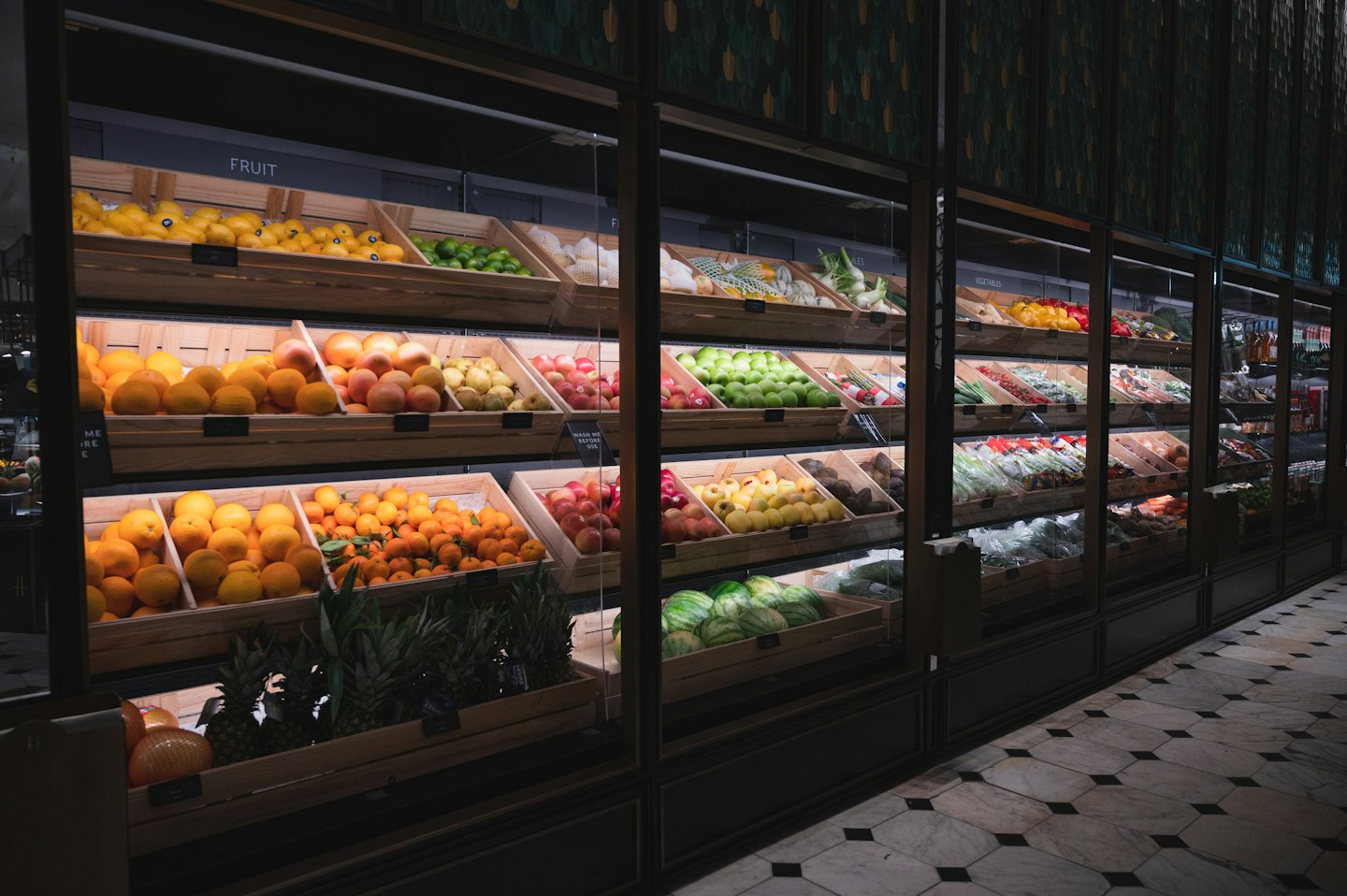 Drewniane skrzynki pełne świeżych owoców i warzyw na półkach supermarketu.