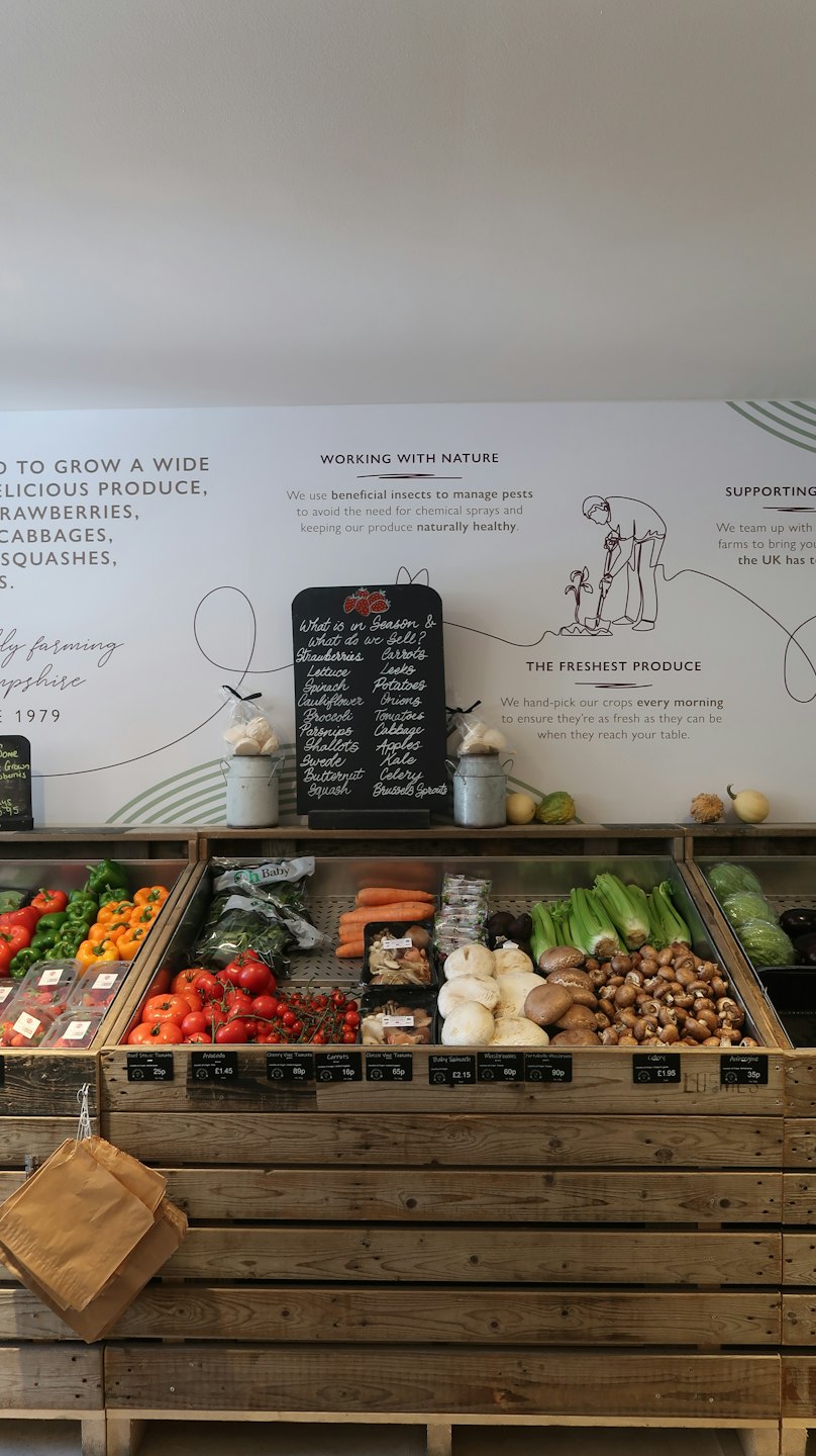 Świeże produkty ułożone w rustykalnych drewnianych skrzyniach w sklepie wiejskim.